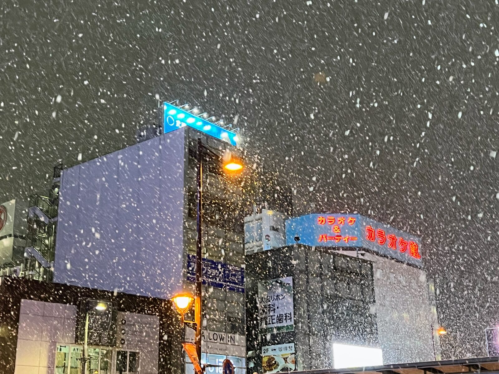 夜空の中、雪が降っている様子（JR大宮駅東口付近）